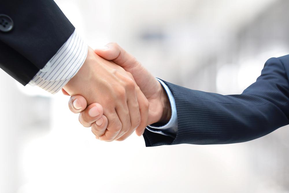 GoDaddy acquires FreedomVoice to bring VoIP services to small businesses. handshake of businessmen