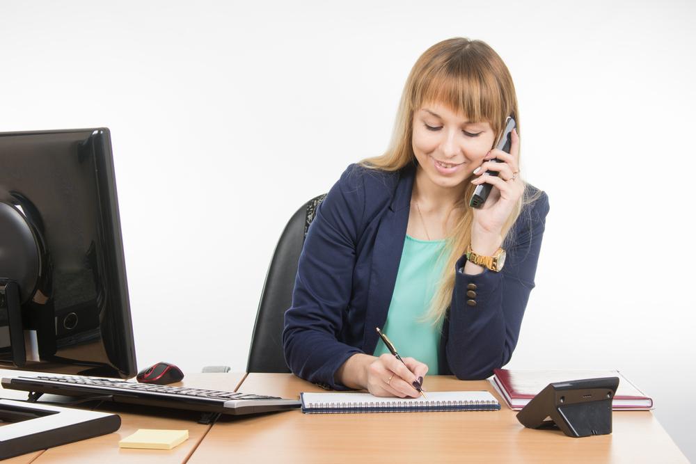 businesswoman taking down notes while on the phone