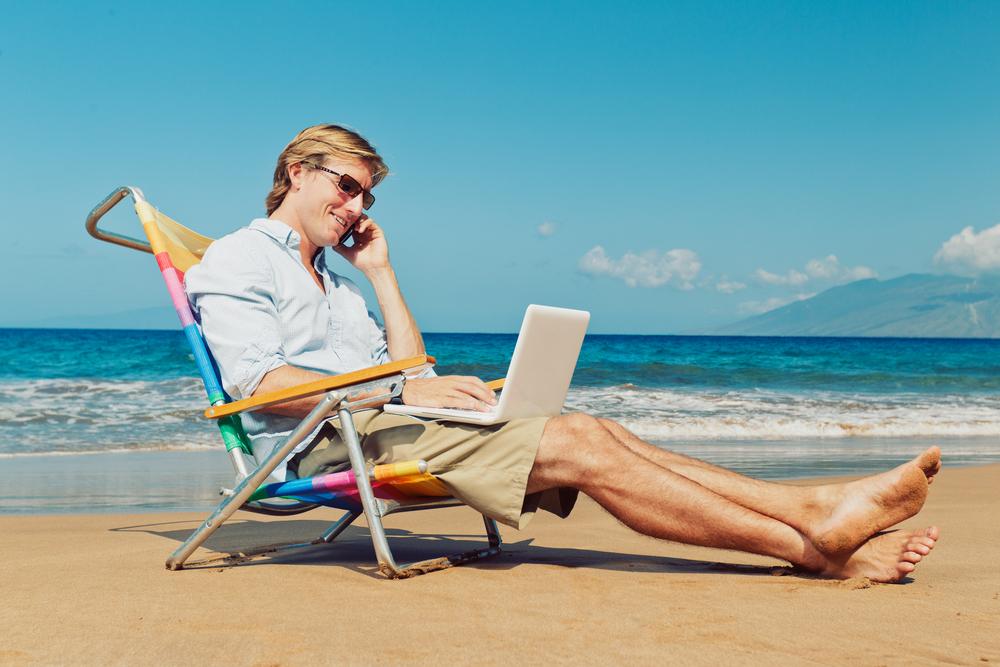 Business man calling by cell phone on the beach