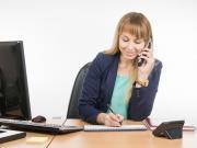 businesswoman taking down notes while on the phone